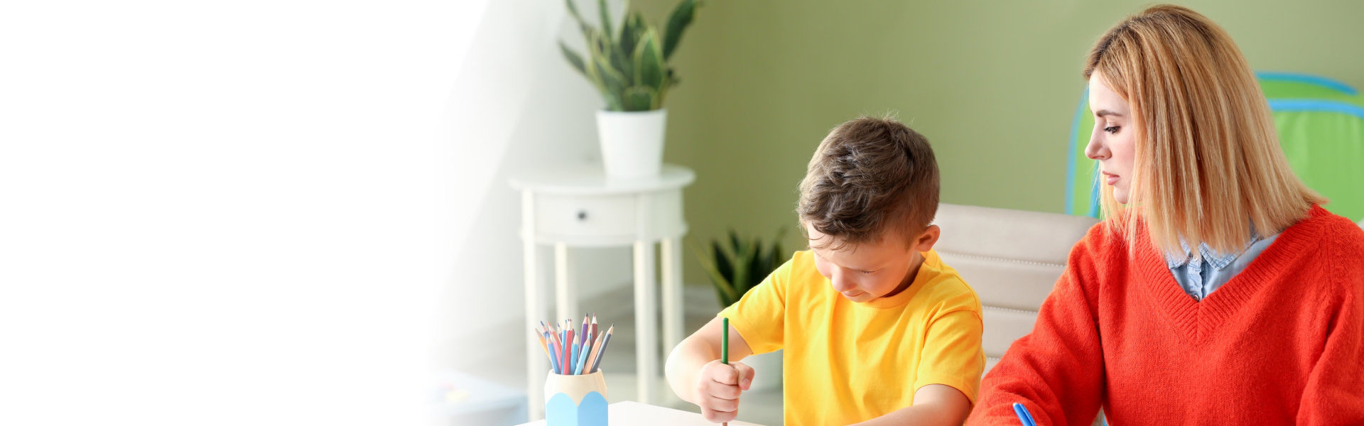 woman with young boy drawing drawing with his color pencils